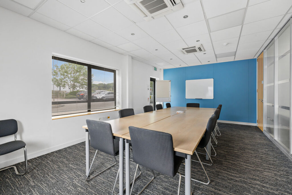 Meeting room laid out for up to 16 people with a projector and screen